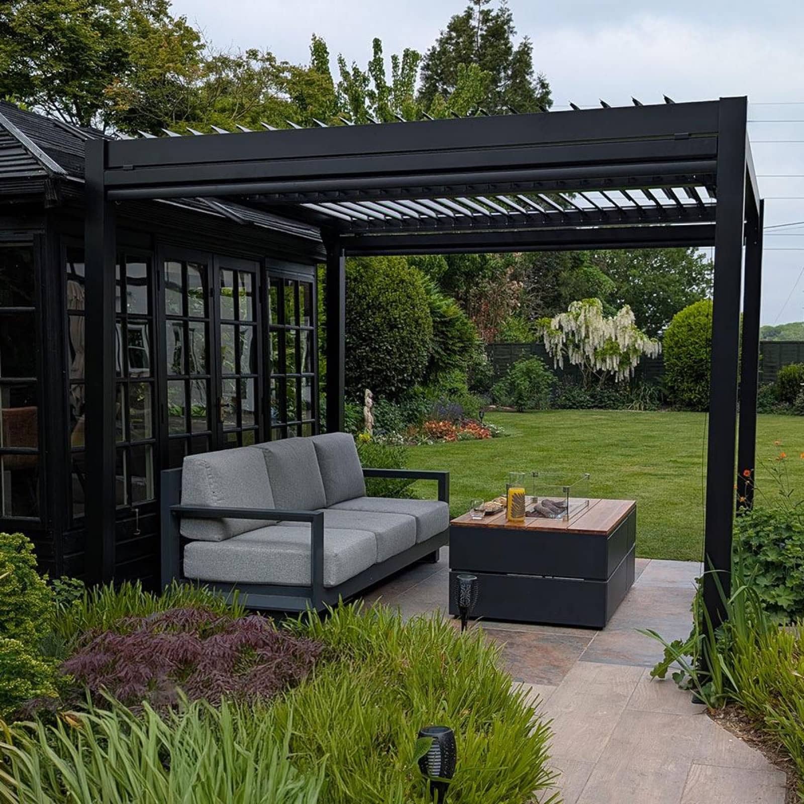 Anthracite aluminium pergola over a furnished garden patio
