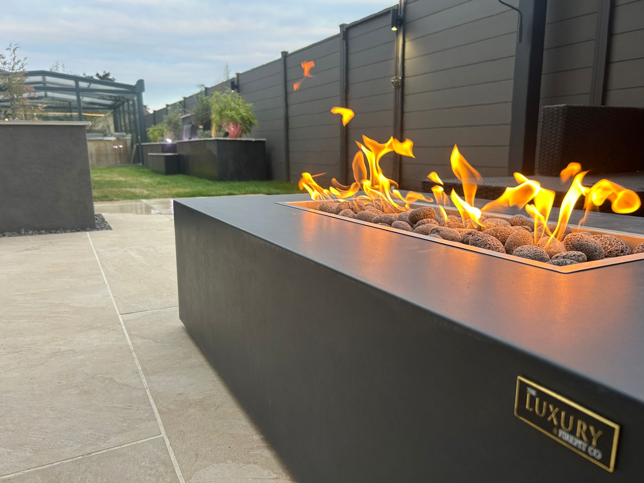 Close view of orange flames over a lava rock bed in a dark modern fire table at dusk